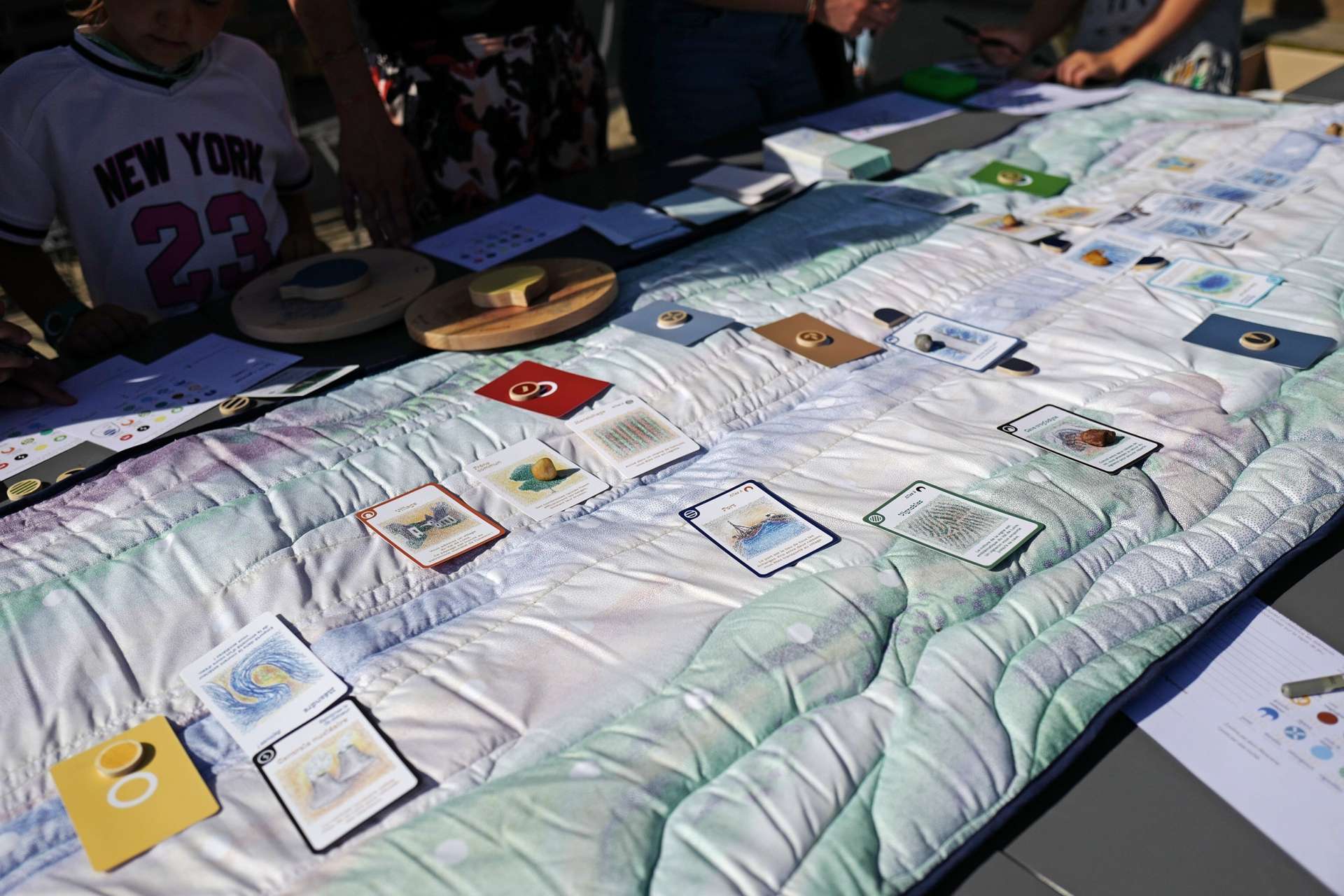 Photo d'un plateau de jeu en tissu représentant, dans un style en pointillisme, la Loire, son lit majeur et le plateau. Des cartes et des pions sont posés dessus.